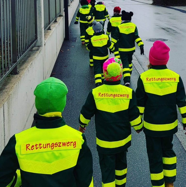 Gruppe af børn i sikkerhedsveste med påskriften "Rettungszwerg" på vej.