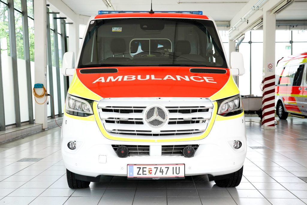 Ambulance vehicle with prominent lettering and modern design in a room for transports.