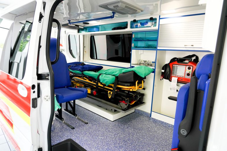 Indvendigt billede af et moderne sygetransportkøretøj med båre og medicinsk udstyr.