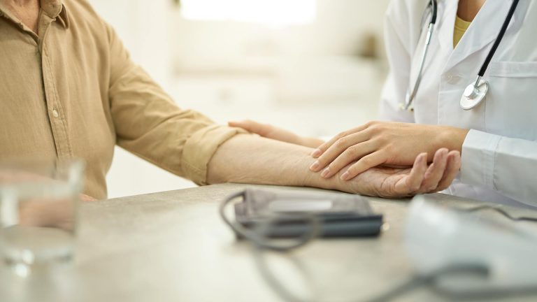 Læge udfører en undersøgelse af en patients arm i en moderne praksis.
