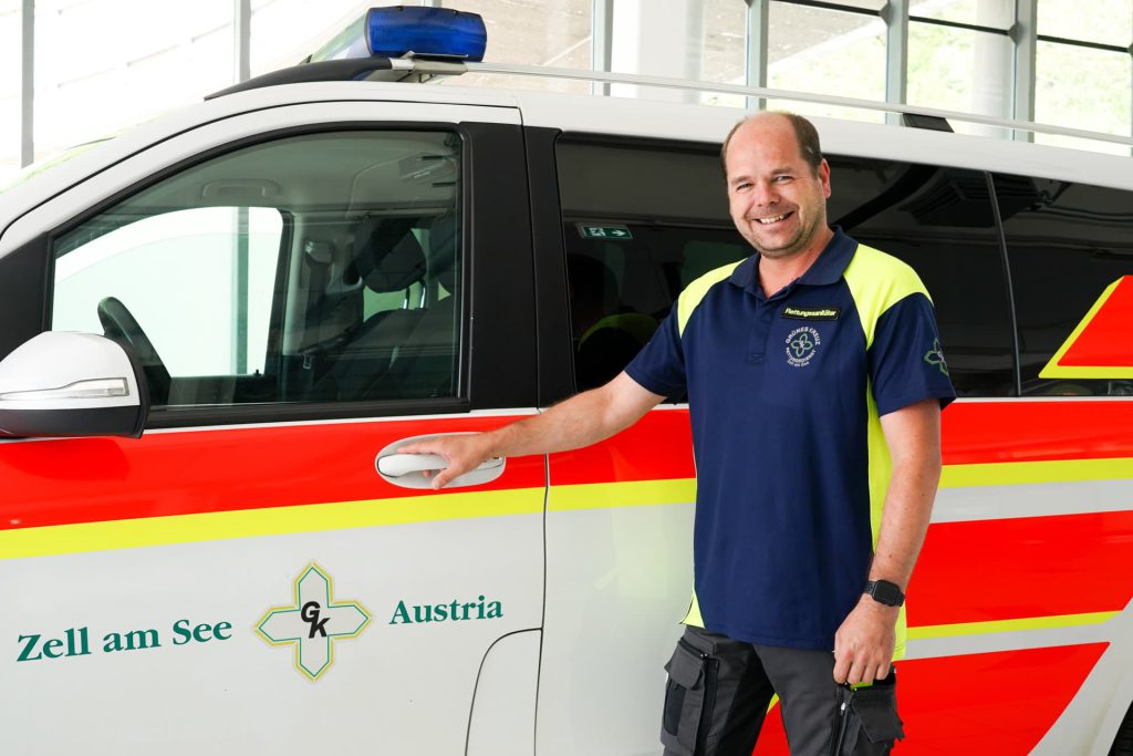 Mitarbeiter des Grünen Kreuzes steht vor einem Krankenwagen in Zell am See.