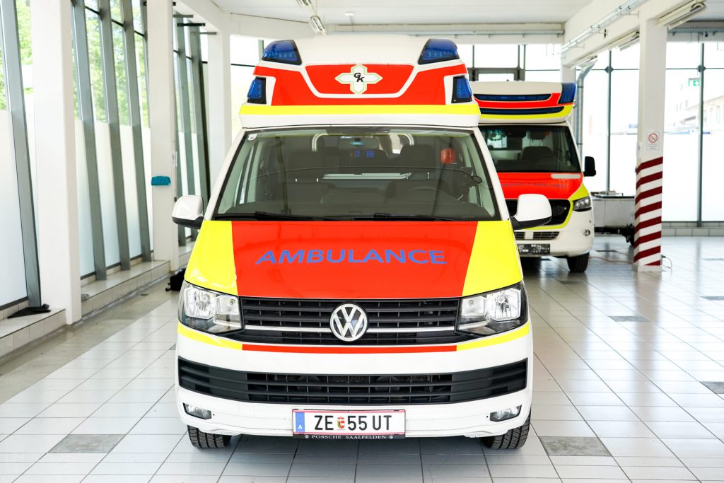 Red and yellow ambulance with 'AMBULANCE' lettering in a modern hall.